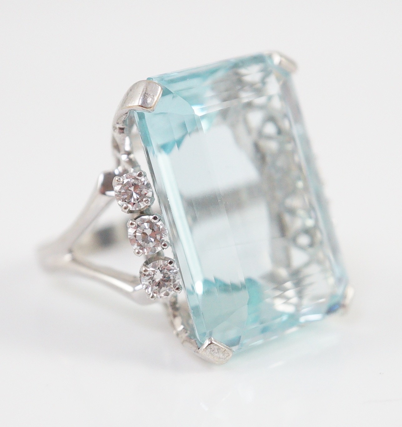 A large modern 14k white gold and emerald cut aquamarine set dress ring, flanked by six round cut diamonds